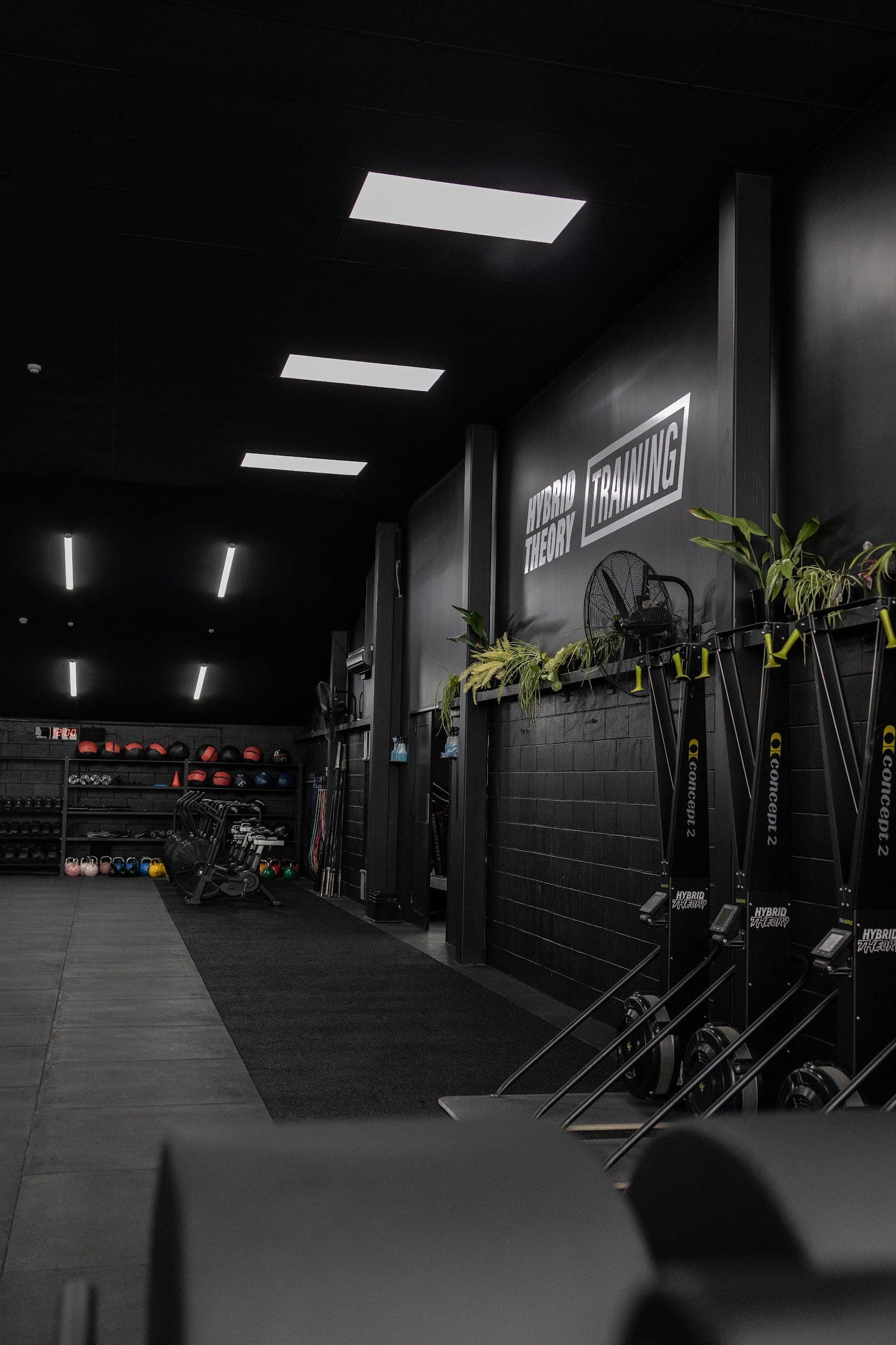 The turf side of the main floor with a wall of Concept2 rowers beneath the Hybrid Theory Training sign