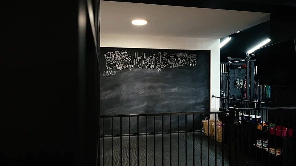 The Hybrid Kids area — a chalkboard wall reading Hybrid Kids, turf flooring and baskets of toys