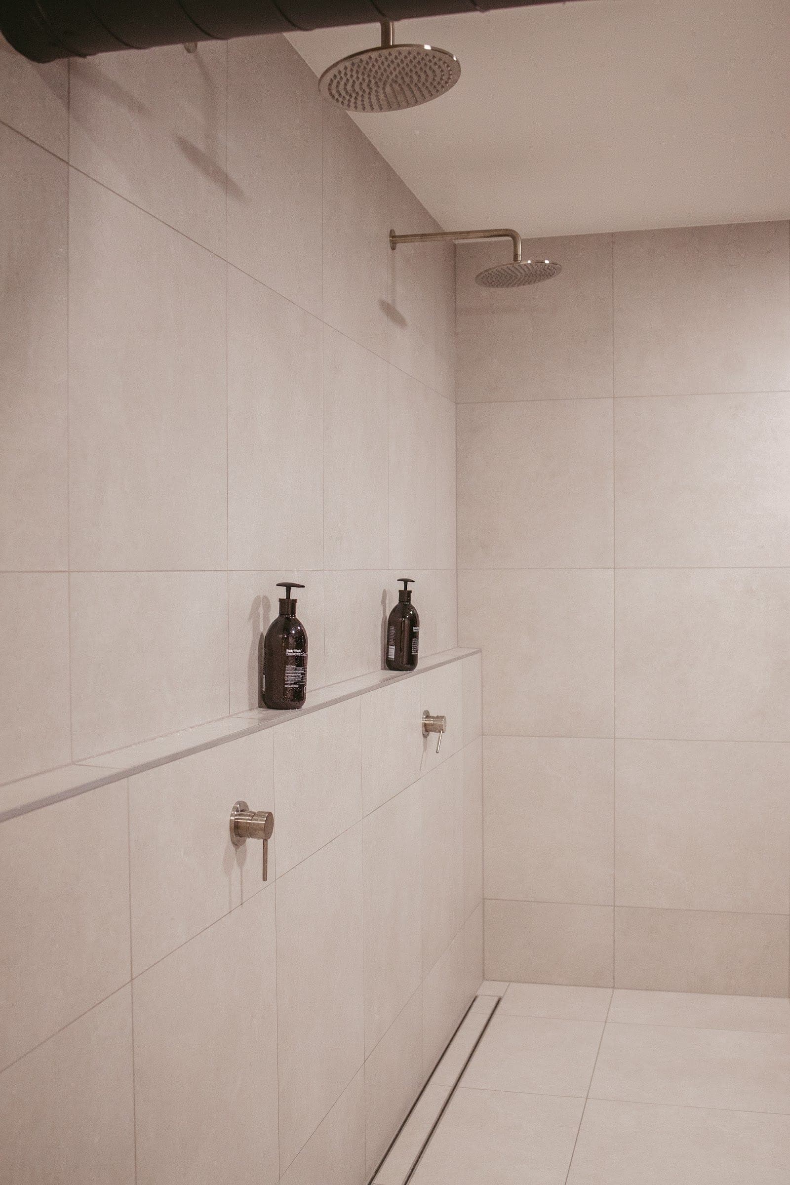Walk-in rainfall showers in the communal ice-bath room, with twin shower heads and stone-look tiling